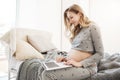 Choosing name for baby. Close up portrait of young attractive blonde pregnant mother in comfy grey home clothes sitting Royalty Free Stock Photo