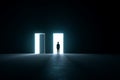 Choosing the Path Silhouette of a person standing before two luminous doors in a dark room symbolizing decision and future Royalty Free Stock Photo