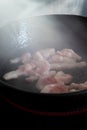 Chopped bacon lardons cooking on a hob in a cast iron frying pan Royalty Free Stock Photo