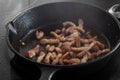 Chopped bacon lardons cooking on a hob in a cast iron frying pan Royalty Free Stock Photo