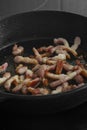 Chopped bacon lardons cooking on a hob in a cast iron frying pan Royalty Free Stock Photo