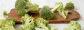 Chopped broccoli on a rustic wooden cutting board on white wooden background, side view. Closeup Royalty Free Stock Photo