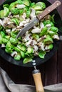 Chopped brussels sprouts and mushrooms in large skillet with knife, preparing vegetarian dinner