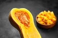 Chopped butternut squash, pumpkin half, fresh vegetable pieces in wooden bowl on black stone table Royalty Free Stock Photo