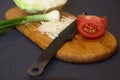 Chopped cabbage, piece of tomato and green onion on a cutting board with a knife Royalty Free Stock Photo