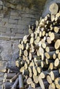 Chopped firewood is stacked in neat piles against background of natural stone wall. Woodpile. Close-up. Selective foc Royalty Free Stock Photo
