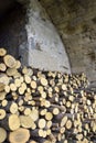 Chopped firewood is stacked in neat piles against background of natural stone wall. Woodpile. Close-up. Royalty Free Stock Photo