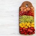Chopped fresh fruits arranged on cutting board on white wooden surface, top view. Ingredients for fruit salad. From above, flat Royalty Free Stock Photo