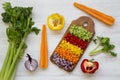 Chopped fresh vegetables arranged on cutting board on white wooden table, top view. From above, overhead, flat lay. Royalty Free Stock Photo