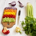 Chopped fresh vegetables carrot, celery, onion, colored peppers arranged on a cutting board on a white wooden surface, side view Royalty Free Stock Photo
