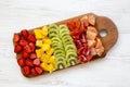 Chopped fruits arranged on cutting board on white wooden background, top view. Ingredients for fruit salad. From above, flat lay, Royalty Free Stock Photo