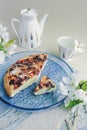 Chopped homemade berry biscuit cake with sugar on a blue transparent glass round plate on a blue napkin and sprig of white flowers