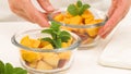 Chopped mangoes and peaches in a glass bowls with mint leaves close up on kitchen table Royalty Free Stock Photo