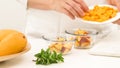 Chopped mangoes and peaches in a glass bowls, woman hands, white background. Royalty Free Stock Photo