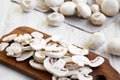 Chopped mushrooms on wooden chopping board, close-up. White wooden background. Royalty Free Stock Photo