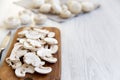 Chopped mushrooms on wooden chopping board over white wooden background, close-up. Side view. Royalty Free Stock Photo