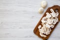 Chopped mushrooms on wooden chopping board, overhead. White wooden background. Flat lay, top view. Royalty Free Stock Photo