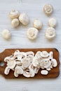 Chopped mushrooms on wooden chopping board, top view. White wooden background. Royalty Free Stock Photo