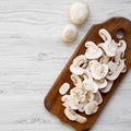 Chopped mushrooms on wooden chopping board on white wooden table, overhead. Flat lay, top view Royalty Free Stock Photo