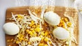 Chopped Peking cabbage, peeled eggs and yellow canned corn on cutting board as a background. Cooking a healthy eco