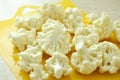 Chopped pieces of cauliflower on yellow cutting board