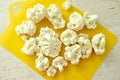 Chopped pieces of cauliflower on yellow cutting board