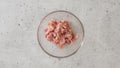 Chopped raw chicken fillet close-up in a glass bowl on a gray stone background, flat lay