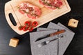 chopped raw pork steaks with spices, tomatoes and thyme on a cutting kitchen board on a black wooden table Royalty Free Stock Photo