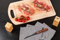 chopped raw pork steaks with spices, tomatoes and thyme on a cutting kitchen board on a black wooden table. next to a napkin with Royalty Free Stock Photo