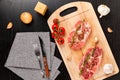 Chopped raw pork steaks with spices, tomatoes and thyme on a cutting kitchen board on a black wooden table. next to a napkin with Royalty Free Stock Photo