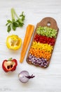 Chopped vegetables arranged on cutting board on white wooden table, high angle view. Royalty Free Stock Photo