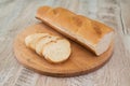 A chopped whole grain baguette lies on a wooden board