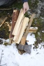 chopped wood for kindling a fire and an axe lie on the ground in winter. a man`s hand holds one log. Royalty Free Stock Photo