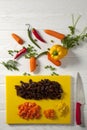 Chopped yellow peppers and carrots. Yellow chopping board and red knife. Green pepper, red hot Royalty Free Stock Photo