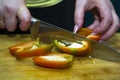 Chopped yellow, red and green peppers and a kitchen knife on a wooden board  on white background Royalty Free Stock Photo