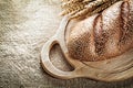 Chopping board bread wheat ears on sacking background Royalty Free Stock Photo