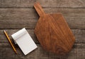 Chopping board and cookbook on wooden background