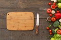 Chopping board and knife near ripe vegetables on wooden table Royalty Free Stock Photo