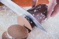 Chopping chocolate dough for pastries with a knife on a wooden board sprinkled with wheat flour