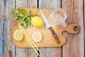 Chopping cutting board, sliced lemon, jar, mint leaves, knife and straw on wooden table. Cocktail preparation. Summer Royalty Free Stock Photo