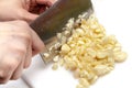 Chopping garlics with knife on white cutting board