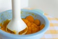 Chopping and mixing boiled or stewed carrots in a bowl with mixer. Preparing baby food, homemade. Healthy food kids concept.