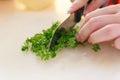 Chopping Parsley with knife on plastic board.