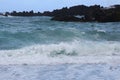 Choppy waters of the Pacific Ocean along a jagged, volcanic rocky shoreline in Waianapanapa State Park