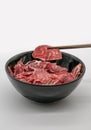 Chopstick holding fresh sliced beef hind shank from black cerami