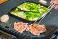 Chopstick holding raw wagyu beef Grill on the electric grill