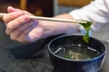 Chopstick holding seaweed from soup