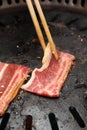 Chopstick holding sliced beef in grill