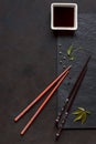 Chopsticks and bowl with soy sauce on black stone background. Asian syile.