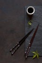 Chopsticks and bowl with soy sauce on black stone background. Asian syile.